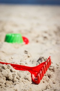 Plastik yeşil tırmık ve diğer oyuncaklar rahatlamak ya da kumsalda oynamak için kullanılıyor. Tatil süresi ve çocuk gelişimi