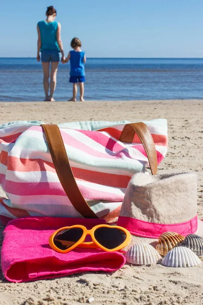 Accessories for relax on sand at beach and mother with son by sea. Travel and vacation time