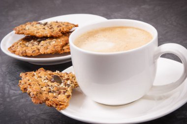 Sütlü kahve ve beyaz tabakta taze ev yapımı yulaf ezmeli kurabiye. Lezzetli çıtır tatlı.