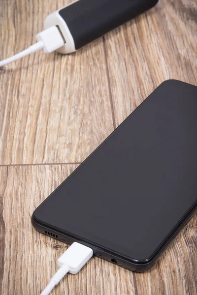 External powerbank using to charge empty battery of black smartphone or mobile phone