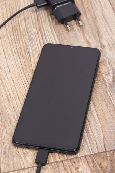 ブラックスマートフォン 充電器付き携帯電話 さまざまなデバイス充電コンセプト — ストック写真