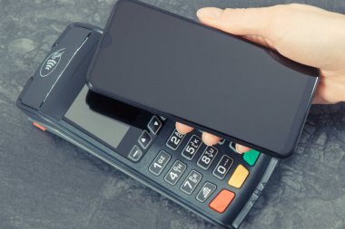 Kredi kartı okuyucu ve cep telefonunu nakit ödemelerde kullanıyor. Ödeme terminali. Finans ve bankacılık kavramı