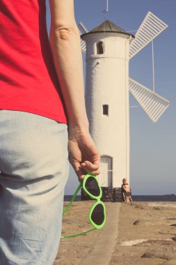 Swinoujscie 'nin batısında güneş gözlüklü bir kadın, karakteristik yön bulma işareti Windmill Stawa Mlyny. Yaz ve tatil zamanı