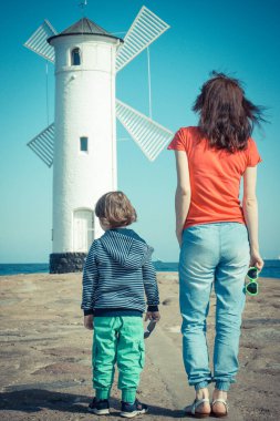 Anne ve oğlu Swinoujscie 'nin batı dalgakıranında, karakteristik yön bulma işareti Windmill Stawa Mlyny ile. Yaz ve tatil zamanı