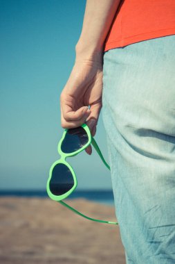 Kalp şeklinde güneş gözlüklü bir kadın eli. Yaz ve tatil zamanı