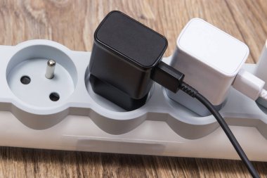 Mobile phone chargers connected to electrical power strip. Various devices charging concept