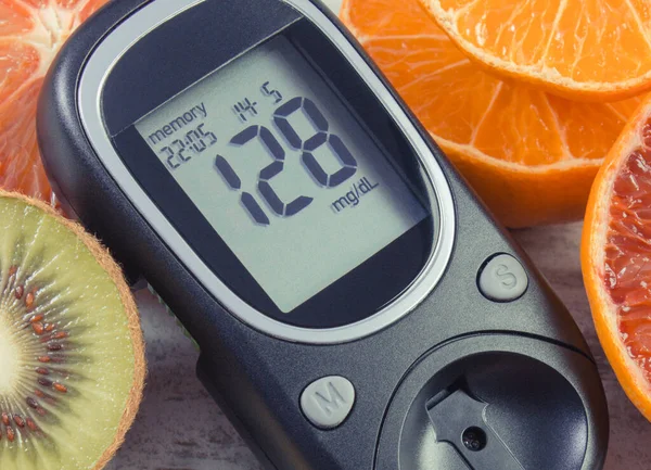 Glucose meter with result of sugar level and fresh natural fruits. Diabetes and healthy lifestyle and nutrition