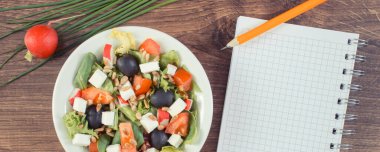 Feta peynirli taze Yunan salatası ve mezuralı not defteri. Zayıflama ve sağlıklı beslenme