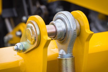 Screws and bolts as part of yellow agricultural machinery. Technology and engineering