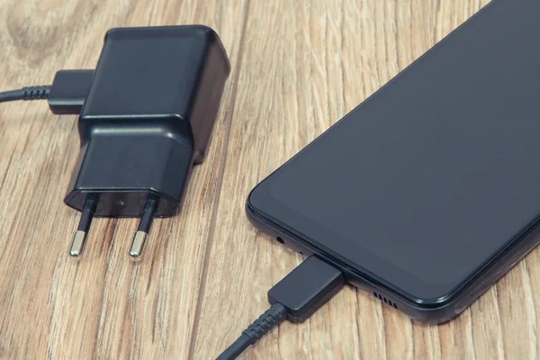 Black smartphone, mobile phone and charger using to charge empty battery. Various devices charging concept