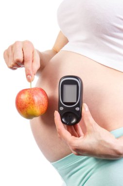 Pregnant woman holding fresh apple and glucose meter for measurement sugar level, concept of healthy nutrition and diabetes during pregnancy