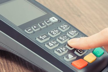PIN kodunu ödeme terminaline giriş yapan bir kadın eli. Alışveriş için para ödemeden. Kredi kartı okuyucu. Finans kavramı