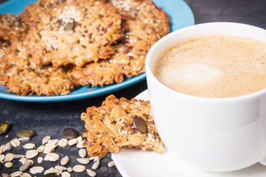Sütlü kahve ve mavi tabakta taze ev yapımı yulaf ezmeli kurabiye. Lezzetli çıtır tatlı.