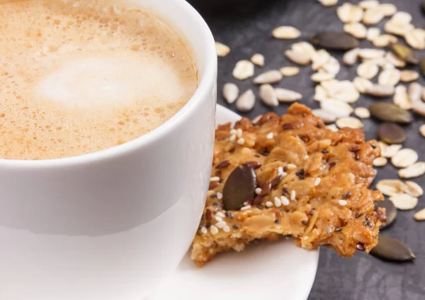 一杯白咖啡和新鲜的自制燕麦饼干 配上蜂蜜和不同的健康种子 美味的脆甜食 — 图库照片