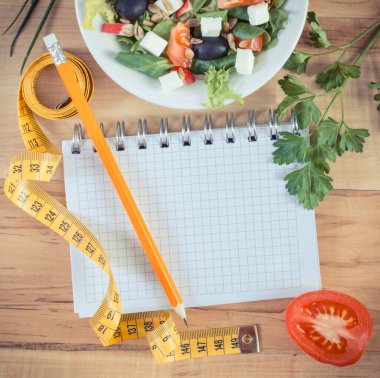 Feta peynirli taze Yunan salatası ve mezuralı not defteri. Zayıflama ve sağlıklı beslenme