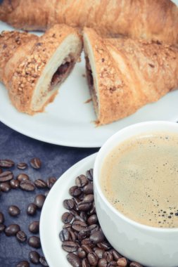 Kahvaltı için beyaz cam kahve ve taze pişmiş kruvasan.