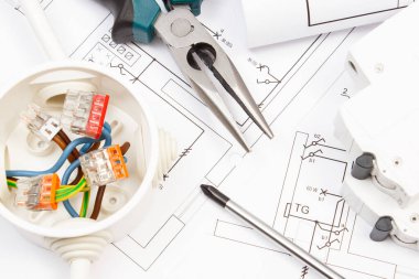 Çalışmalar için kullanılan metal araçlar, elektrik sigortası ve elektrik tesisatı ile bağlantılı renkli kablolar ve konut planının diyagramları ile elektrik tesisatı. Ev konsepti inşa ediliyor