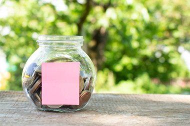Ahşap bir masanın üzerinde bozuk paralar olan cam bir kavanoz. Yatırım için bütçe. Mali konsept.