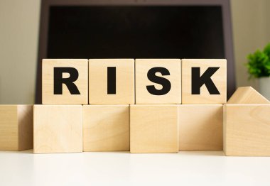 RISK kelimesi ofis masasında dizüstü bilgisayarın önünde duran tahta küplere yazılmıştır. İş konsepti.