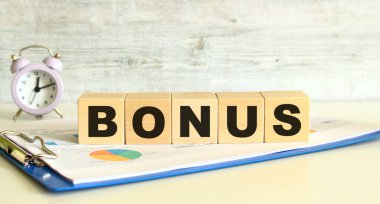 Tahta küpler, gri arka planda mali tabloların olduğu bir klasörde yatıyor. Küpler 