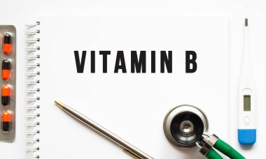 Masa ve steteskop üzerinde duran bir not defterine yazılmış VITAMIN B metni. Tıbbi konsept.