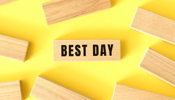 Ordet bästa dag är skrivet på en träkloss på en gul bakgrund. — Stockfoto