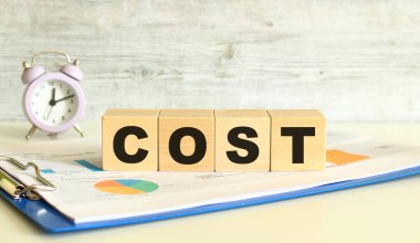 Tahta küpler, gri arka planda mali tabloların olduğu bir klasörde yatıyor. Küpler 