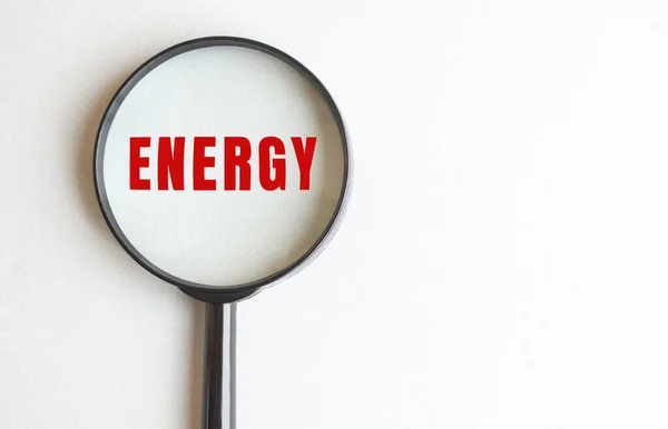 ENERGY text written on gray background. We read it through a magnifying glass. — Stock Photo, Image