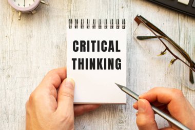 El, CRITICAL 'in kalemle düşünme metnini bir deftere yazar. Yukarıdan görüntüle.