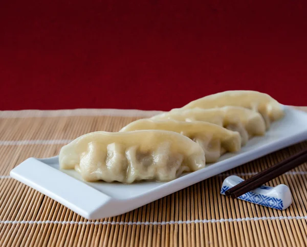 Gyoza or potstickers on a plate over a bamboo mat with copy spac — Stock Photo, Image