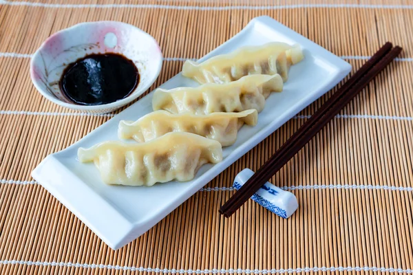 Delicious gyoza or pot stickers on bamboo mat — Stock Photo, Image