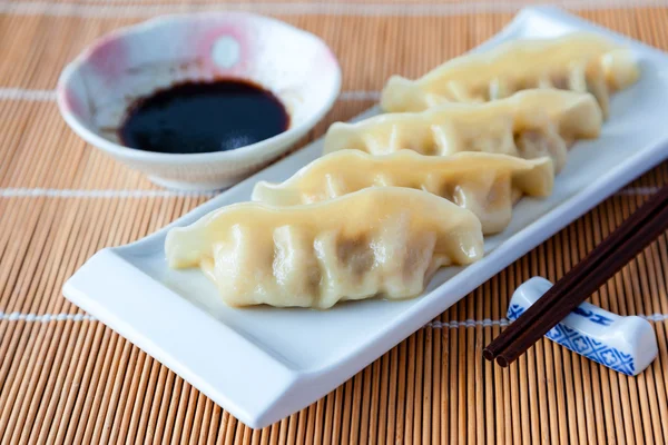 Delicious gyoza or pot stickers on bamboo mat — Stock Photo, Image
