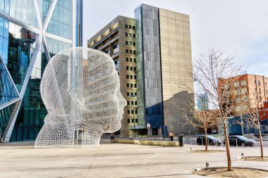 CALGARY, CANADA - 13 numara. 2021: Caume Plensa 'nın Harikalar Diyarı heykeli Calgary şehir merkezindeki Bow Tower' ın önünde, Alberta, Kanada.