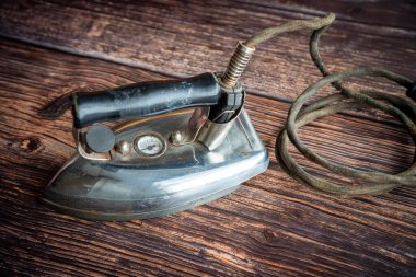 Ahşap arka planda ahşap saplı ve kordonlu kıyafetler için eski moda elektrikli ütü..