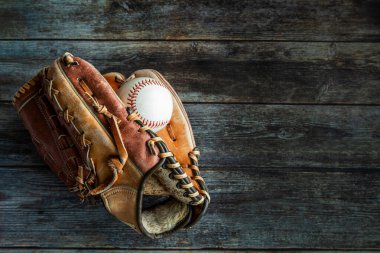 Leather baseball or softball glove with ball on rustic wooden background with copy space.