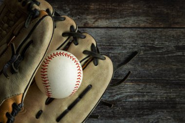 Leather baseball or softball glove with ball on rustic wooden background with copy space.