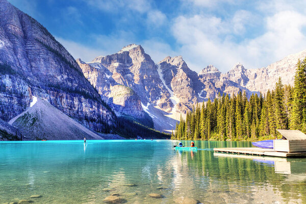 Unidentifiable visitors canoeing their boats on turquoise-colored Moraine Lake in the Canadian Rockies of Banff National Park near Lake Louise. The Valley of the Ten Peaks in the background.