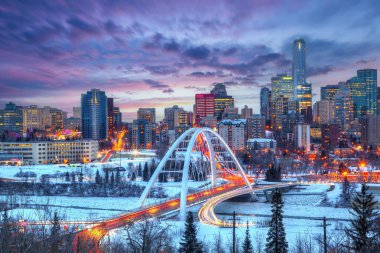 Trafik ışıkları Edmonton şehir merkezinde kış günbatımında Walterdale Köprüsü 'nü donmuş, karla kaplı Saskatchewan Nehri ve etrafındaki gökdelenleri gösteriyor..