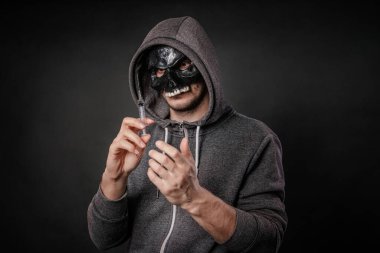 Siyah kafatası maskeli bir bağımlı şırıngaya bir doz uyuşturucu alıyor. Uyuşturucu ölüm konsepti.