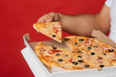 Yakın plan bir adamın elleri kırmızı arka planda pizza tutuyor. Fast food