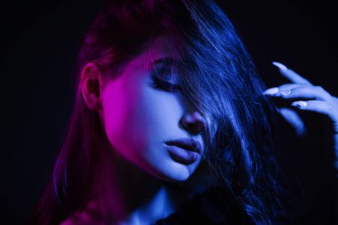 Kulüpteki karanlıkta genç bir kadın. Mavi ve pembe elbiseli kız. Siber tarzda güzel bir model portresi