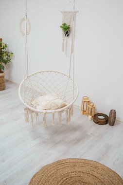 Hasır sallanan sandalye büyük parlak bir odada iplerin üzerinde. İskandinav tarzı iç mekan. Yerde yuvarlak örülmüş halı.