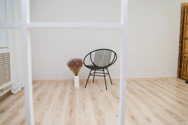 白い壁に対するウィッカーロフトスタイルの黒い椅子 床にドライフラワーで花瓶 ミニマルなインテリア — ストック写真