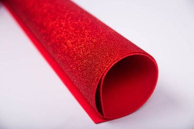 Beyaz arka planda parıldayan kalın kırmızı bir kağıt rulo. Yaratıcılık için parlak kumaş. İzole et