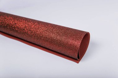 Beyaz arka planda parıltılar olan koyu kahverengi bir kağıt rulo. Yaratıcılık için parlak kumaş. İzole et