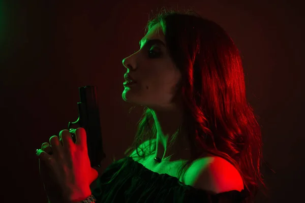クラブで暗闇の中で美しい若い女性が銃を手に持っている 赤緑色の女の子のシルエット — ストック写真