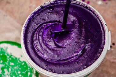 Mor duvar boyası. Tamir için bir kova boyayı karıştırıyor. fuşya rengi