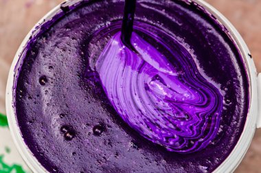 Mor duvar boyası. Tamir için bir kova boyayı karıştırıyor. fuşya rengi