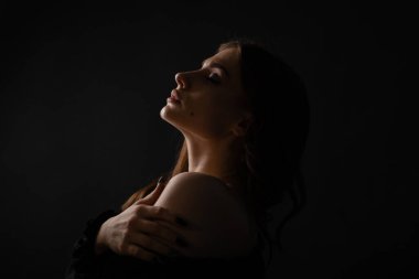 Karanlık bir arka planda güzel bir kızın seksi silueti. Portre. Stüdyoda şık bir fotoğraf var..