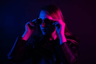 Geceleri parlayan pembe neon şehrin yakınında uzun saçlı tatlı bir kız. Genç bir kadının boyalı mavi pembe saçları. Yuvarlak gözlüklü gizemli yeniyetme. Siber punk ışık yansıması.